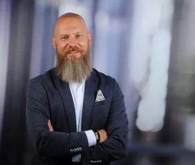 Christian Kalb: Oberkörperporträt eines Herrn mit blaulichem Anzug und einem auffälligen Bart.