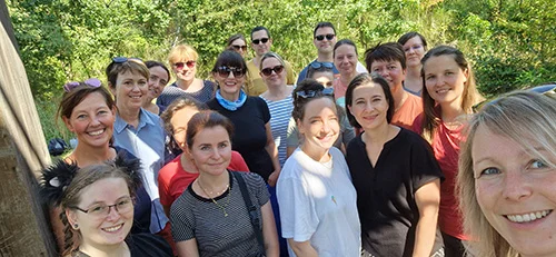 Selfie des Teams in sommerlicher Kleidung vor grünen Pflanzen im Hintergrund